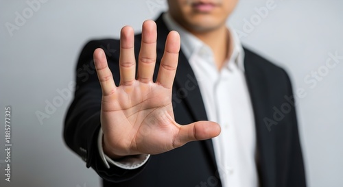 A man in a business suit holds up his hand with palm facing forward in a stop or halt gesture, indicating refusal or prohibition.