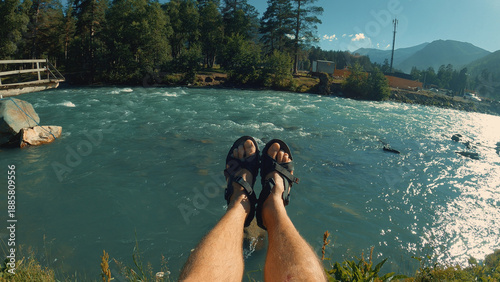Canvas Print First-person perspective of a man relaxing, feet dangling over a turbulent turquoise river