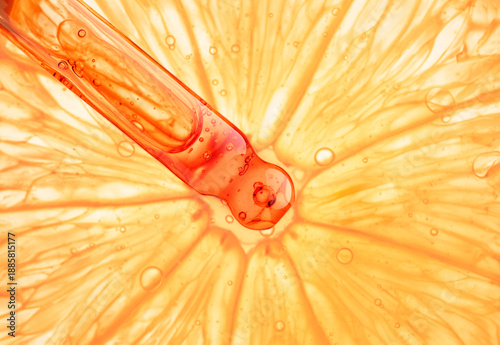 Close-up of a cosmetic dropper with liquid serum over fresh grapefruit and orange slices. Beauty product sample swatch of citrus-based skincare oil or facial essence with vitamin C, featuring natural 