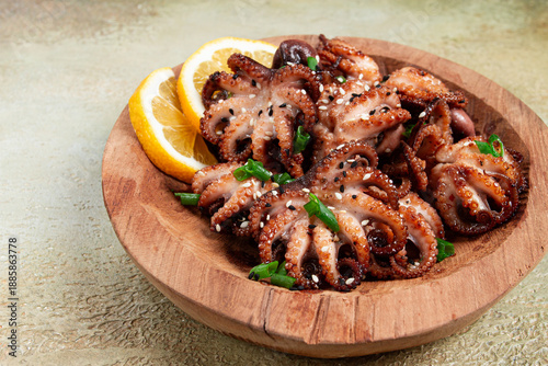 grilled baby octopus with green onions, lemon slices, on a wooden plate, homemade, no people,