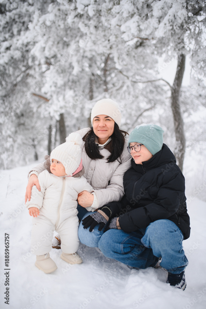 Obraz premium Mother and children enjoying snowy winter forest together