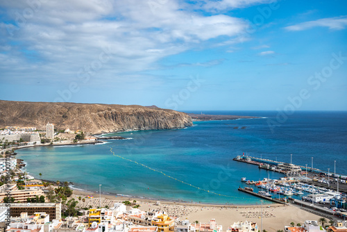 A coastal resort with turquoise and clear waters and a small port for boats and ships