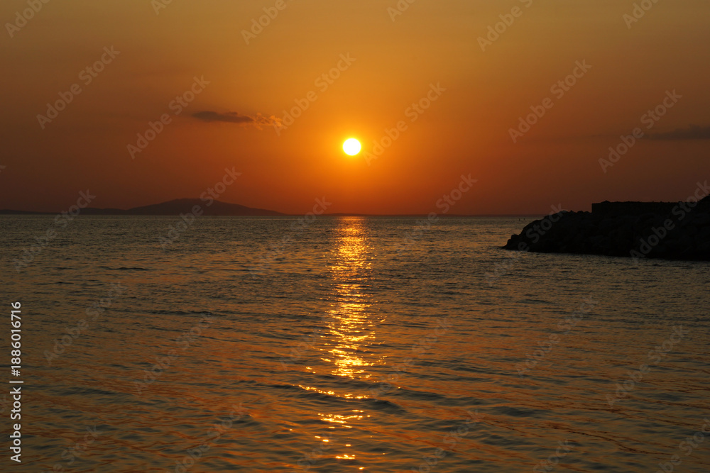 Obraz premium Golden sunset over the sea with sun reflection on wavy seawater