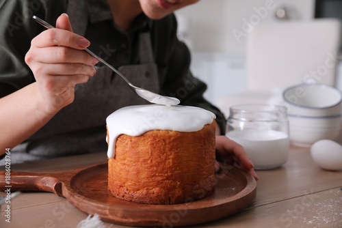 Foto Young woman decorating traditional Easter cake with glaze in kitchen, closeup
