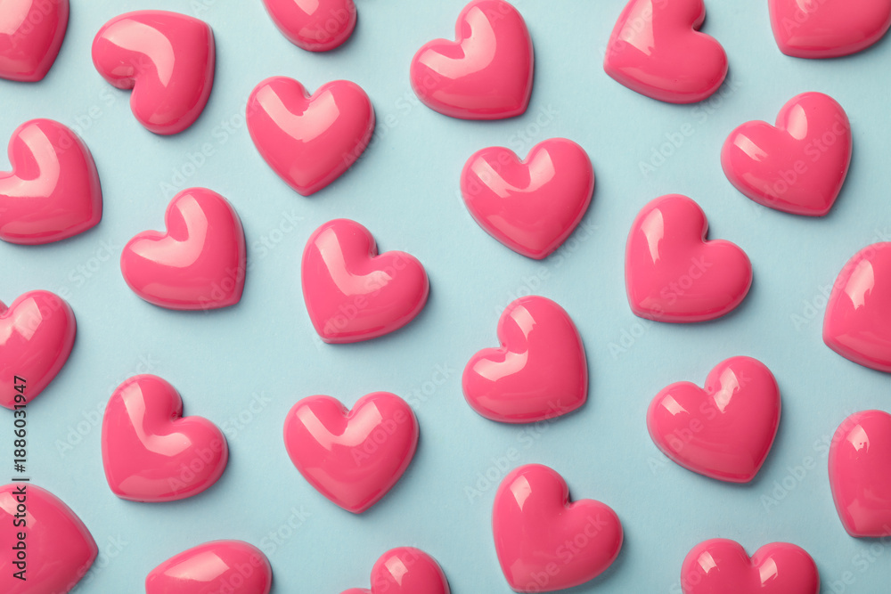 Fototapeta premium Pink decorative hearts on light blue background, flat lay