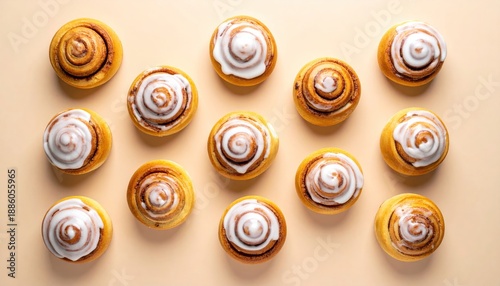 Delicious Freshly Baked Cinnamon Rolls with Sweet White Icing, Arranged on a Light Beige Background, Top View.