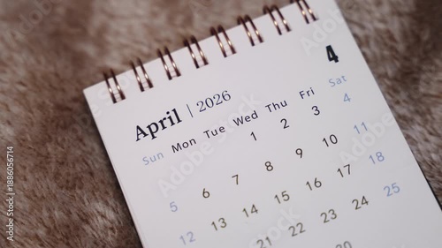 Close-up of April 2026 calendar page with finger pointing at date, concept of planning, scheduling and time management.