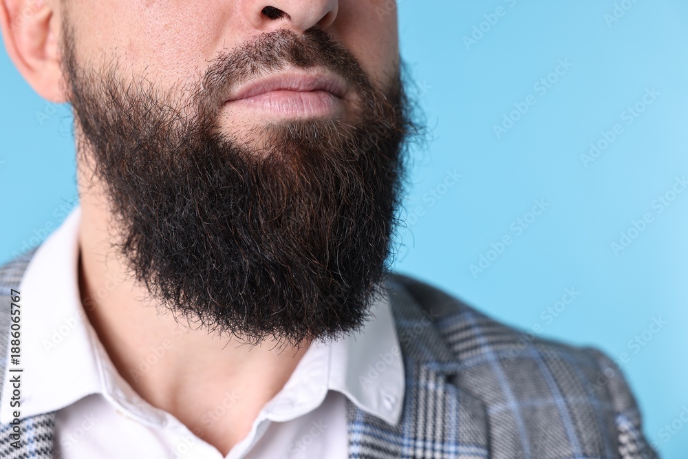 Obraz premium Man with mustache and beard on light blue background, closeup. Space for text