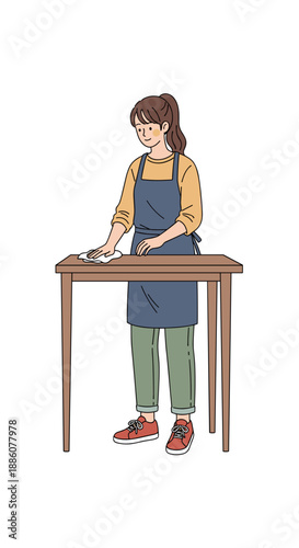 Young woman cleaning table while wearing an apron at home  
