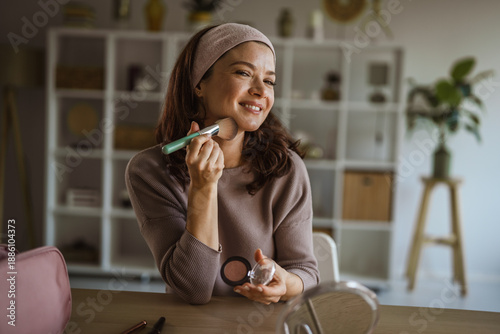 Photos Young woman applying makeup blush to her cheek