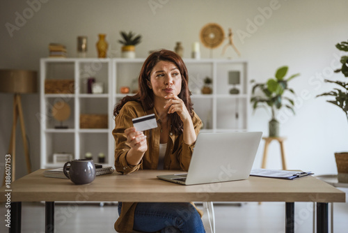 Photos Woman making online purchase decision with credit card at home
