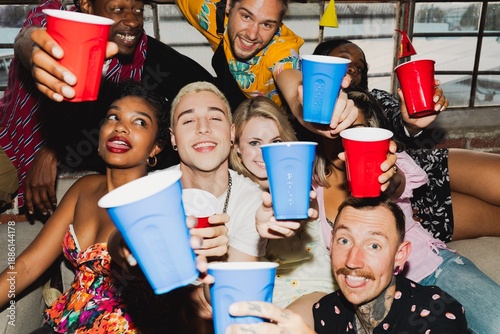 Sticker Group of diverse friends celebrating with red and blue cups, smiling and laughing