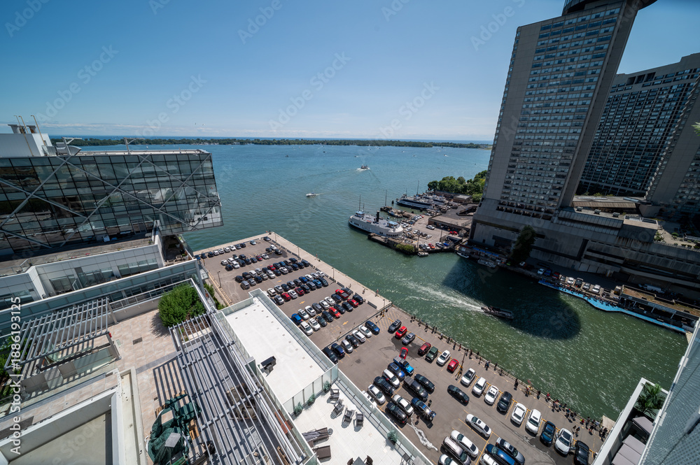 Fototapeta premium Elevated view of the toronto harbourfront, showing modern buildings, boats docked in the marina, and a wide expanse of lake ontario under a clear blue sky