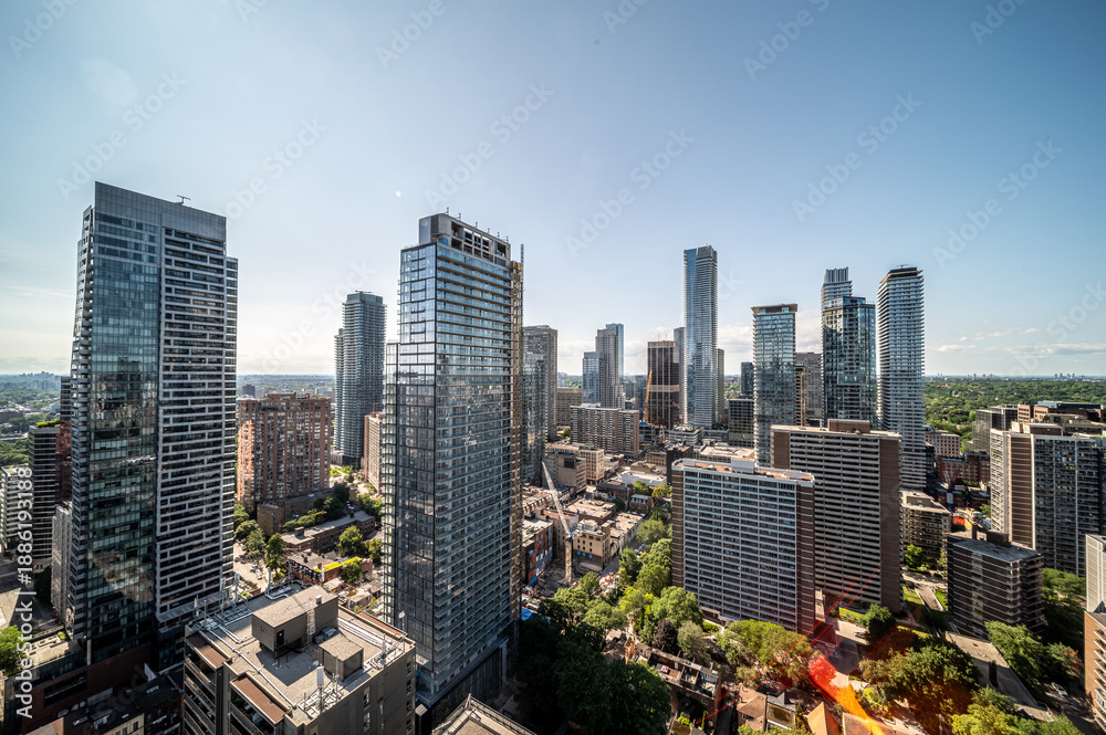 Obraz premium Urban skyline presenting numerous high rise residential and commercial buildings under a clear blue sky, illustrating city development and modern architecture