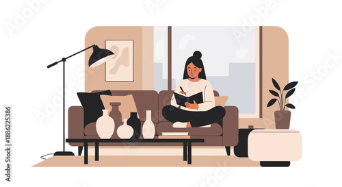 Young woman sitting on sofa writing in notebook at home.