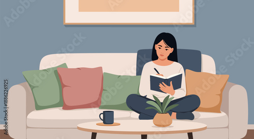 Young woman writing in a notebook while sitting comfortably on a sofa.