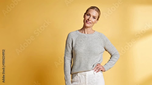 Smiling woman in casual outfit against bright yellow background