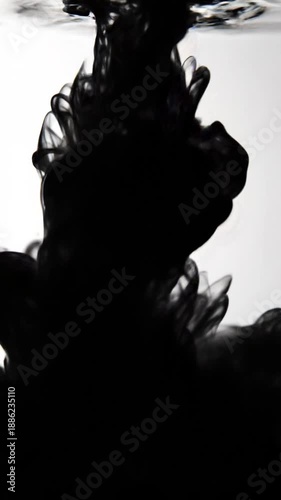 Elegant black ink splashing in clear water creating artistic pattern