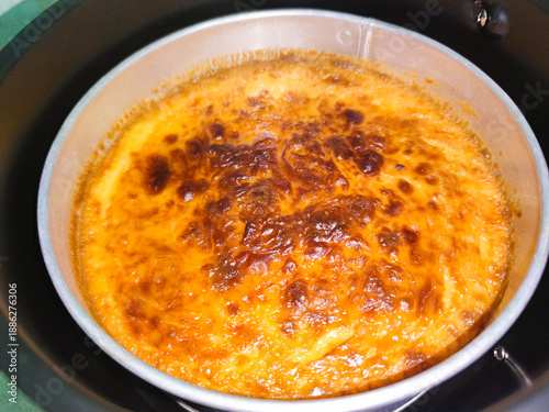 Schilderij op canvas Top view of a baked custard with a deeply caramelized surface, cooked in a metal pan