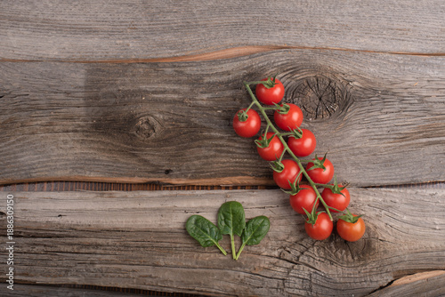 Cherry tomatoes and spinach leaves on wooden background. Top view. No people.