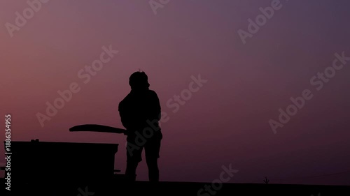 Unrecognized cricket player silhouette standing with bat during evening golden hour. Clean sports background footage for cricket reels, tournament visuals, promotional videos, and broadcast design.