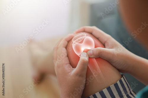 Tableau sur toile Close-up of child hand holding painful injured knee with red inflamed spot and X-ray bone skeleton joint overlay