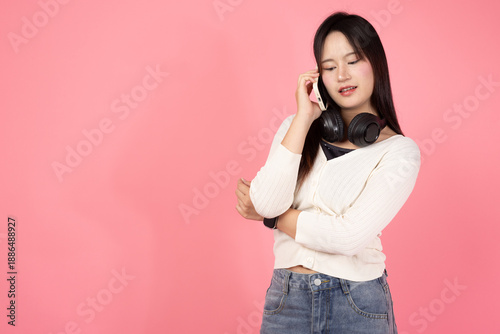 Happy Thai smiling confident A woman is talking on her cell phone while wearing headphones