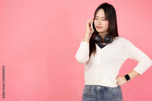 Happy smiling confident A woman wearing headphones and a white sweater is talking on her cell phone