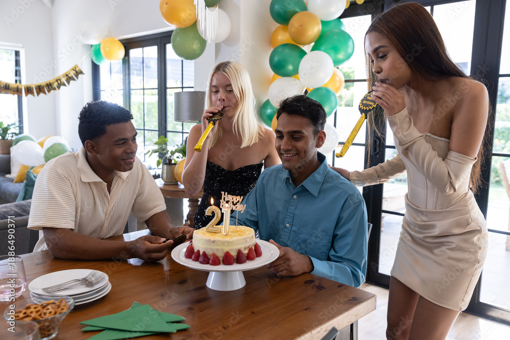 Obraz premium Diverse friends gathering around table at home celebrating birthday cake, balloons