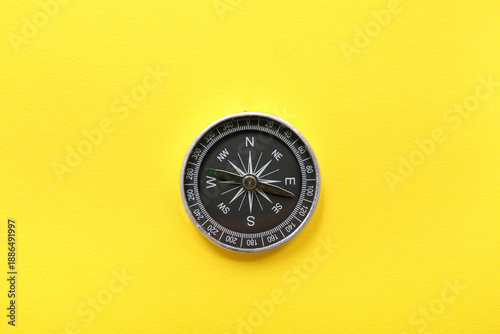 Modern compass on yellow ba...