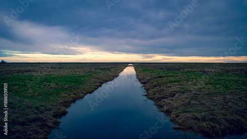 Stormy sunset at Freiston Shore, Lincolnshire with a still mirror-like dyke ditch going off to infinity point.