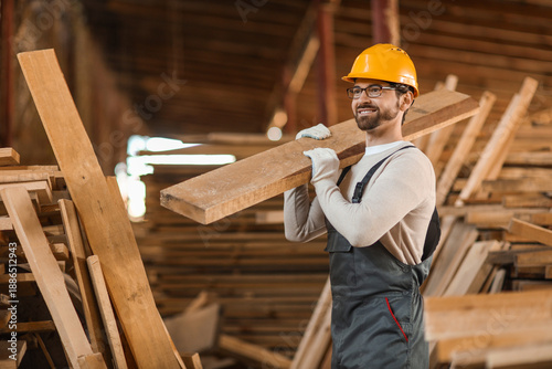 Male carpenter carrying woo...