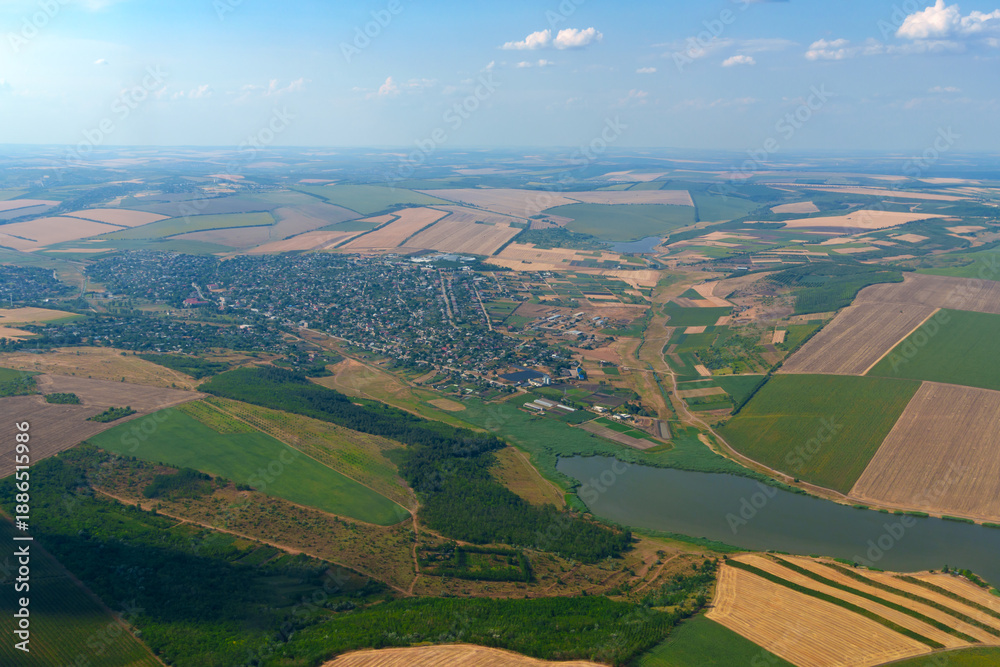 Obraz premium Detailed aerial view from airplane window of a small town with lake and surrounding green fields
