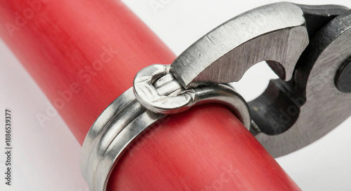 Removing stainless steel cinch clamp from red PEX pipe using cutting pliers