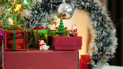 A festive Christmas gift and decoration set featuring red, green, and gold tones, arranged with a Christmas tree, decorative lights, and gift boxes. Creates a warm, cheerful atmosphere perfect for hol