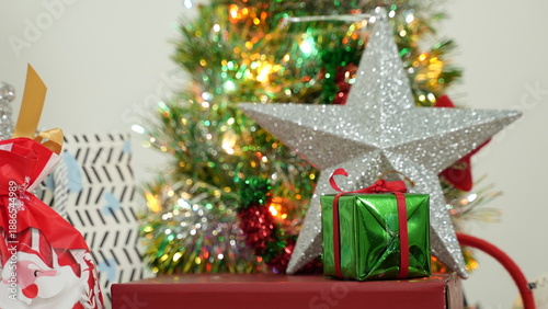 A festive Christmas gift and decoration set featuring red, green, and gold tones, arranged with a Christmas tree, decorative lights, and gift boxes. Creates a warm, cheerful atmosphere perfect for hol