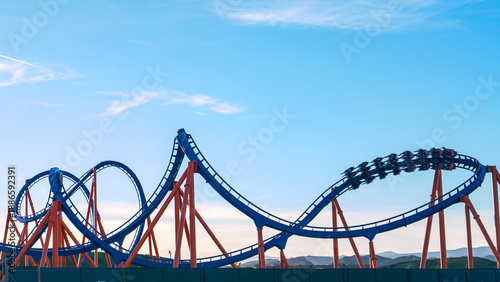 Bild auf Leinwand CLOSE UP: Cool shot of a roller coaster driving into a twister on sunny evening
