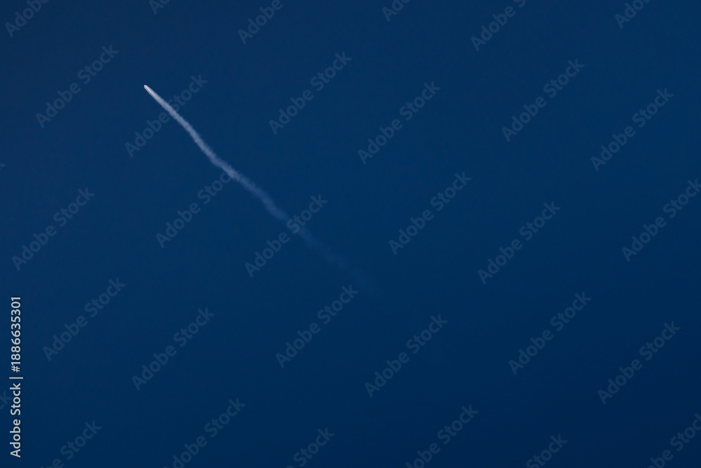 Fototapeta premium Rocket launches into clear blue sky leaving white trail