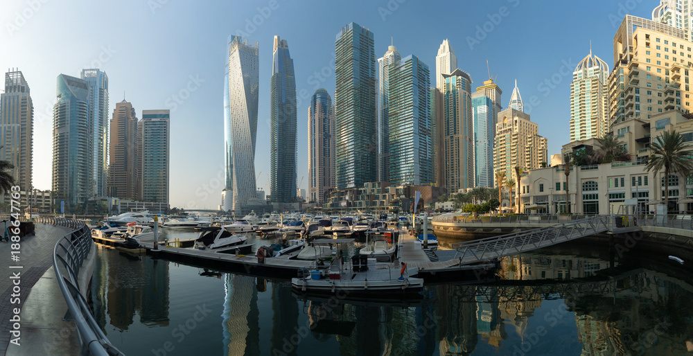 Obraz premium Evening view of a river canal and a ship. Orange sunlight, skyscrapers, buildings and the embankment. On the streets of the Emirates, in a public place.