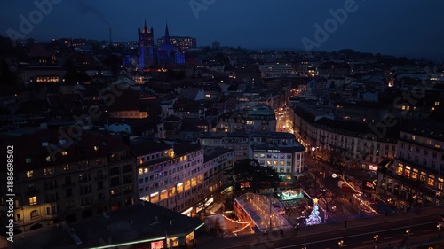 Wallpaper Mural Aerial view of the illuminated Lausanne Cathedral towers over the city's Christmas market, creating a festive glow, Lausanne, Vaud, Switzerland. Torontodigital.ca