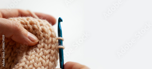 Canvas Print Close-up of woman hands crocheting warm beige wool yarn with blue metal hook
