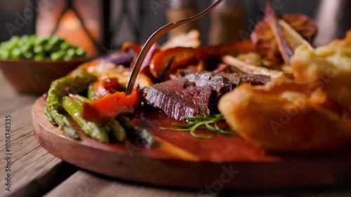 Close up panorama of a fork cutting and lifting a piece of roasted sweet potato. Healthy Sunday roast dinner with beef and vegetables on a board