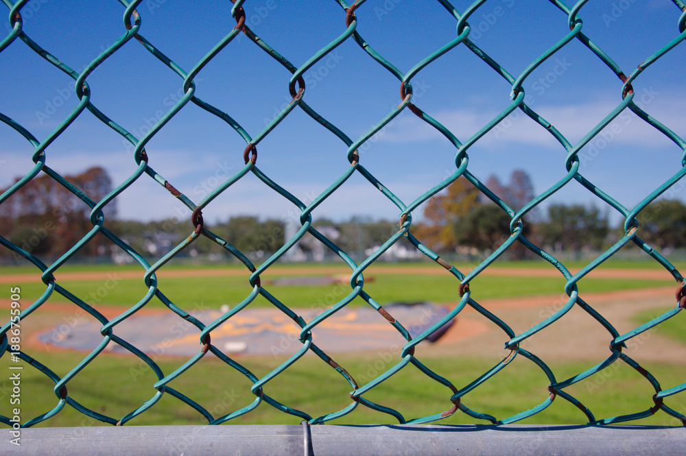 Fototapeta premium Baseball Field With Dugout, Fencing, and Green Grass Under Clear Blue Sky, Sunny Park. Crescent Lake Park old Spring Training facility St. Petersburg, FL. Historic 