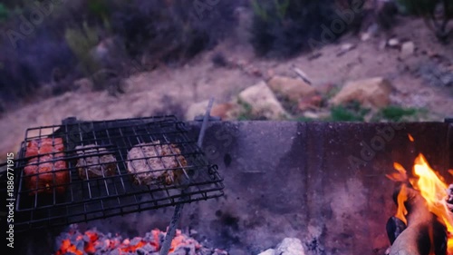 BBQ grilling burgers over a fire pit. Smoke from the cooking adds to the ambiance Cederberg, South Africa