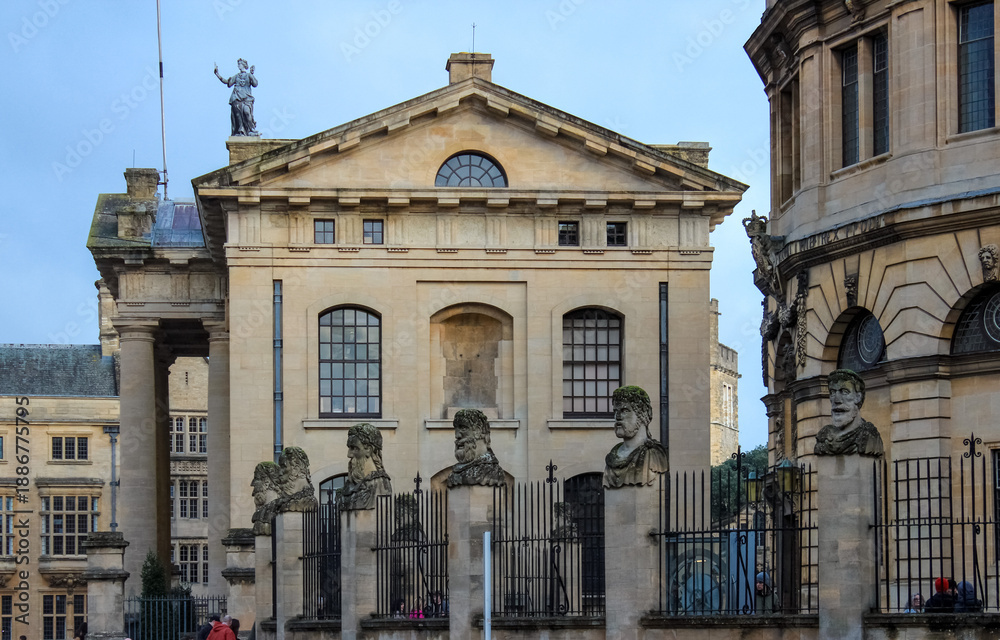 Obraz premium The Clarendon Building in Oxford, which stands next to the Sheldonian Theatre and the Bodleian Library complex. The iconic stone heads lining the front of the buildings.
