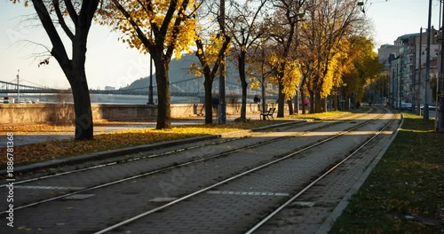 Budapest, Hungary - November 9, 2025: Timelapse, slide transition. Scenic autumn view of tram tracks along the tree-lined Danube embankment in Budapest Hungary