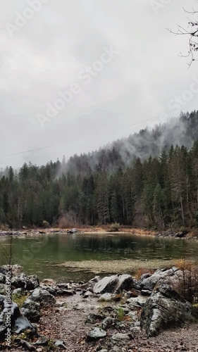 A peaceful vertical real-time video showing rain falling on a clear alpine lake.