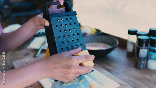 A close-up view of a person grating cheese onto a plate