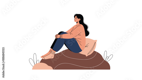 Young woman with long dark hair sits comfortably on a large brown cushion or rock in a relaxed and peaceful meditation pose.