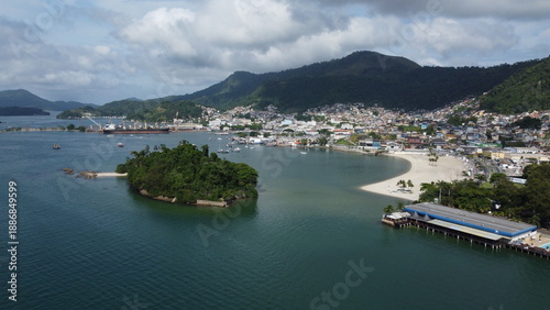 Fotografie Wide coastal view of Angra dos Reis in Brazil showing sandy beach areas, urban waterfront, and tropical mountains rising behind the town